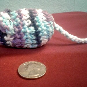 May include: A crocheted mouse toy with a long tail. The mouse is made with blue, purple, and white yarn. The tail is white.
