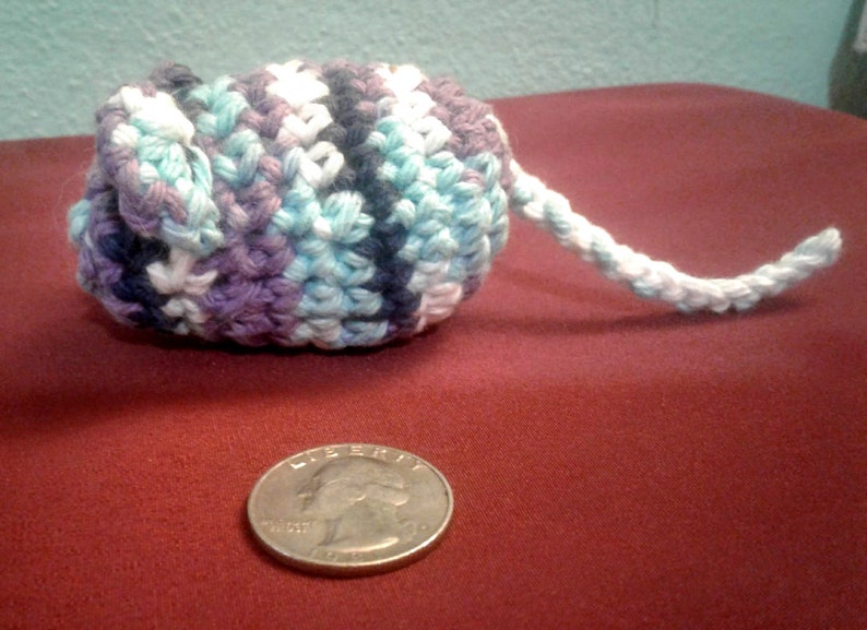 May include: A crocheted mouse toy with a long tail. The mouse is made with blue, purple, and white yarn. The tail is white.