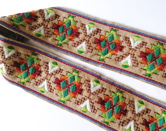 May include: A beige fabric trim with a colorful embroidered pattern. The pattern features green, red, orange, and white geometric shapes.