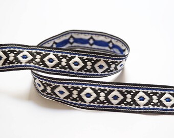 Könnte beinhalten: Schwarz-weiße Borte mit einem blauen geometrischen Muster. Die Borte ist gewebt und hat einen dezenten Glanz.