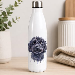 May include: A white stainless steel water bottle with a silver screw-top lid. The front of the bottle features a detailed watercolour-style illustration of a black curly-haired dog's face with blue paint splatters and drips at the bottom.