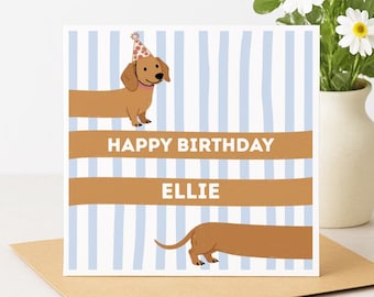 Puede incluir: Tarjeta de cumpleaños con una ilustración de perro salchicha. La tarjeta presenta un fondo a rayas azules y blancas con las palabras "HAPPY BIRTHDAY ELLIE". El perro salchicha lleva un gorro de fiesta.