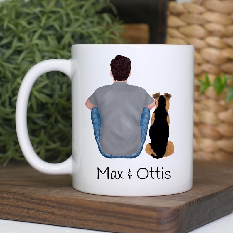 K&ouml;nnte beinhalten: Wei&szlig;e Keramik-Tasse mit einer individuellen Illustration einer Person und eines Hundes. Die Person tr&auml;gt ein graues T-Shirt und blaue Jeans. Der Hund ist schwarz und braun. Auf der Tasse stehen die Namen "Max & Ottis".
