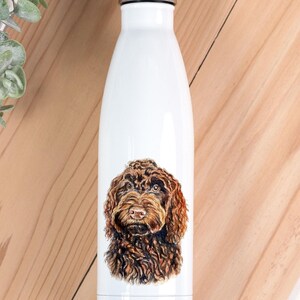 May include: A white stainless steel water bottle with a silver screw-top lid. The front of the bottle features a detailed, realistic illustration of a brown, curly-haired dog, resembling a Labradoodle or Goldendoodle, centred on the body.
