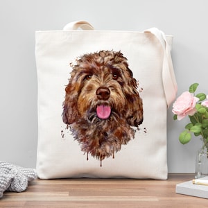 May include: A brown and white dog with a pink tongue sticking out is painted on a white tote bag. The dog's fur is painted in a watercolour style with brown and white splotches.