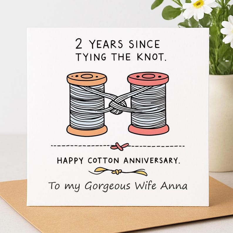 May include: A square greeting card with a white background featuring an illustration of two thread spools, one orange and one pink, tied together with a knot. The text reads: 2 YEARS SINCE TYING THE KNOT. HAPPY COTTON ANNIVERSARY. To my Gorgeous Wife Anna.