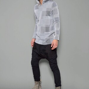 May include: A person wearing a gray and black striped long-sleeved hooded shirt with black pants and gray boots.