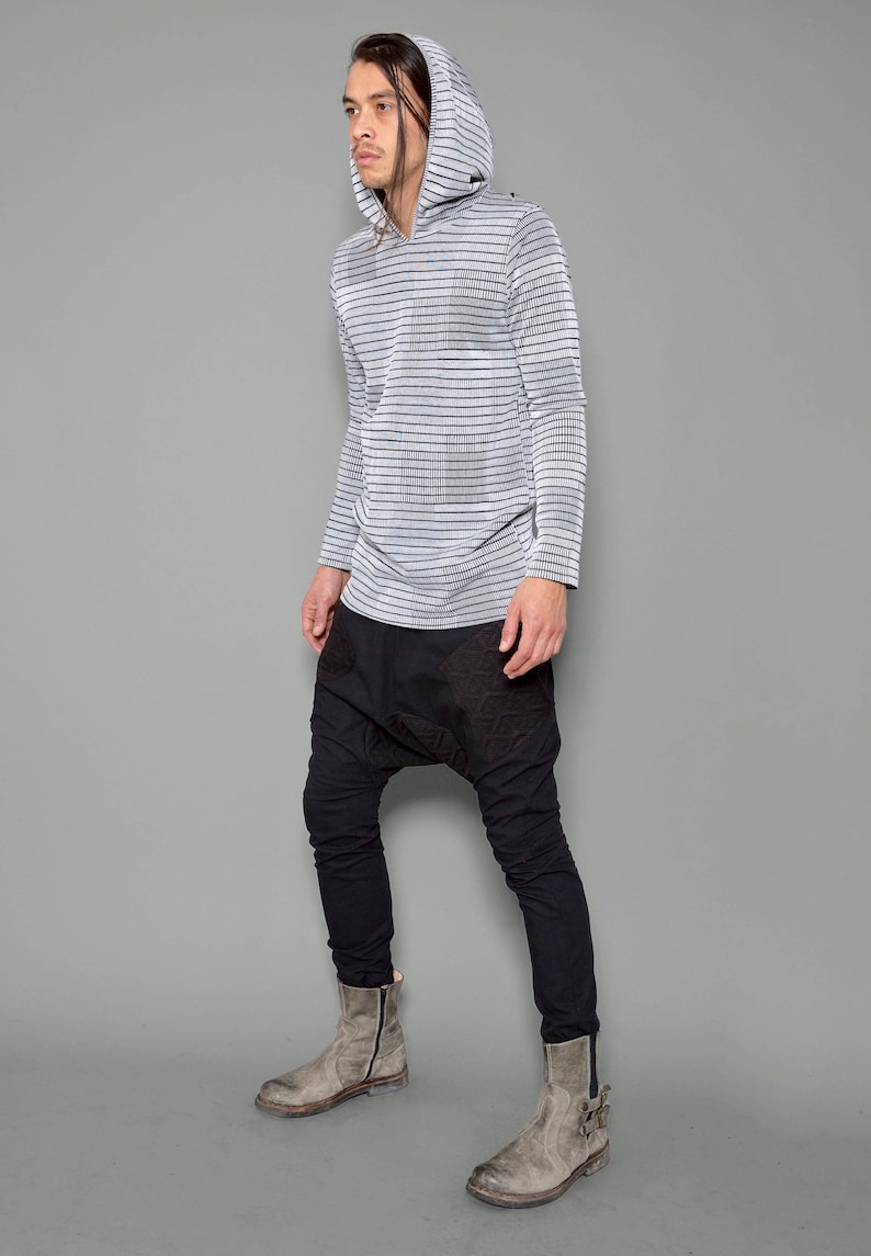 May include: A person wearing a gray and black striped long-sleeved hooded shirt with black pants and gray boots.