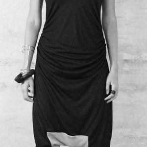 May include: A black and gray jumpsuit with a draped design. The jumpsuit has a scoop neck and thin straps. The model is wearing black platform sandals.