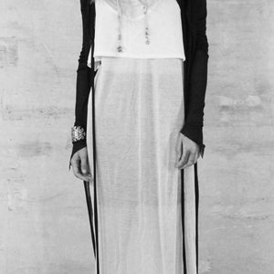 May include: A black hooded cardigan with long sleeves and a white sheer maxi dress. The cardigan has a long, flowing silhouette and the dress has a simple, elegant design.
