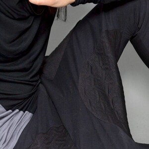 May include: Black long-sleeved shirt with a cowl neck and black pants with a geometric pattern.