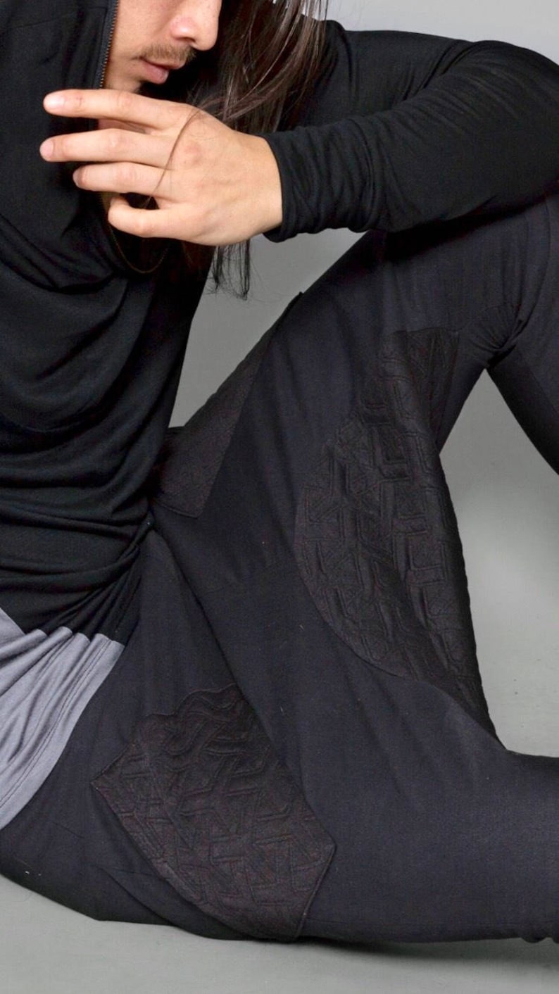 May include: Black long-sleeved shirt with a cowl neck and black pants with a geometric pattern.