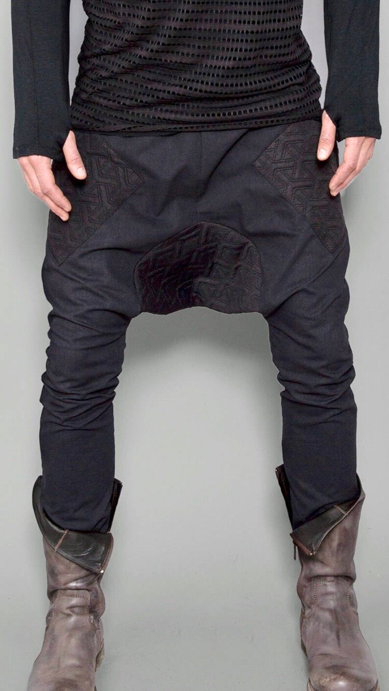 May include: Black pants with a unique design featuring embroidered details and a gathered crotch. The pants are made of a soft, comfortable fabric and have a relaxed fit.