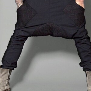 May include: Black pants with a unique design featuring geometric patterns on the pockets. The pants are made of a soft, stretchy fabric and have a relaxed fit.