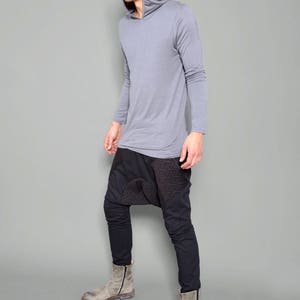 May include: A gray long-sleeved hooded shirt with a black and gray patterned pants and gray boots.