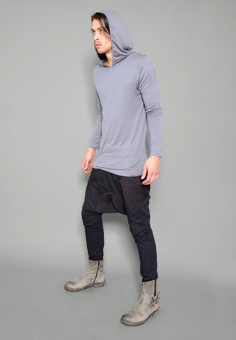 May include: A gray long-sleeved hooded shirt with a black and gray patterned pants and gray boots.