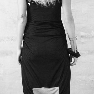 May include: A black jumpsuit with a white panel on the back. The jumpsuit has a loose fit and is made of a soft, stretchy fabric. The model is wearing the jumpsuit with a pair of black sandals.
