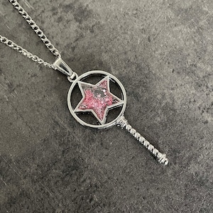 Könnte beinhalten: Eine silberne Halskette mit einem sternförmigen Anhänger. Der Stern ist mit rosa Glitzer gefüllt.