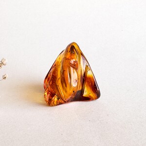 Peut inclure: Une grande pièce d'ambre de forme irrégulière, de couleur ambre, avec un motif en spirale. L'ambre est translucide et a une teinte dorée chaude.