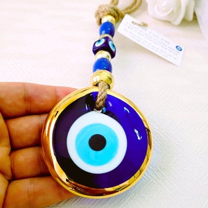 May include: A blue and gold evil eye charm with a blue eye and white pupil. The charm is attached to a gold chain with blue beads.