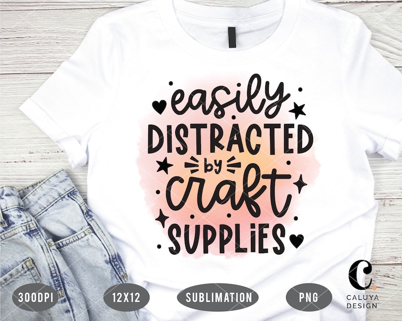 Puede incluir: Camiseta blanca con un fondo de acuarela rosa y texto negro que dice "f&aacute;cilmente distra&iacute;do por los suministros de manualidades".