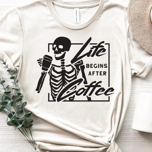 May include: A white t-shirt with a black skeleton holding a coffee cup and the text "Life Begins After Coffee".