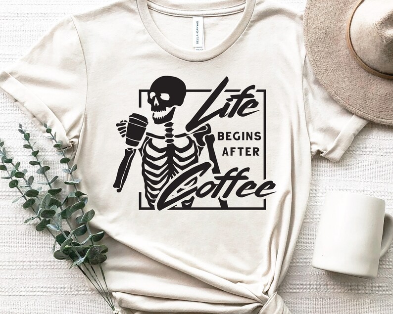 May include: A white t-shirt with a black skeleton holding a coffee cup and the text "Life Begins After Coffee".