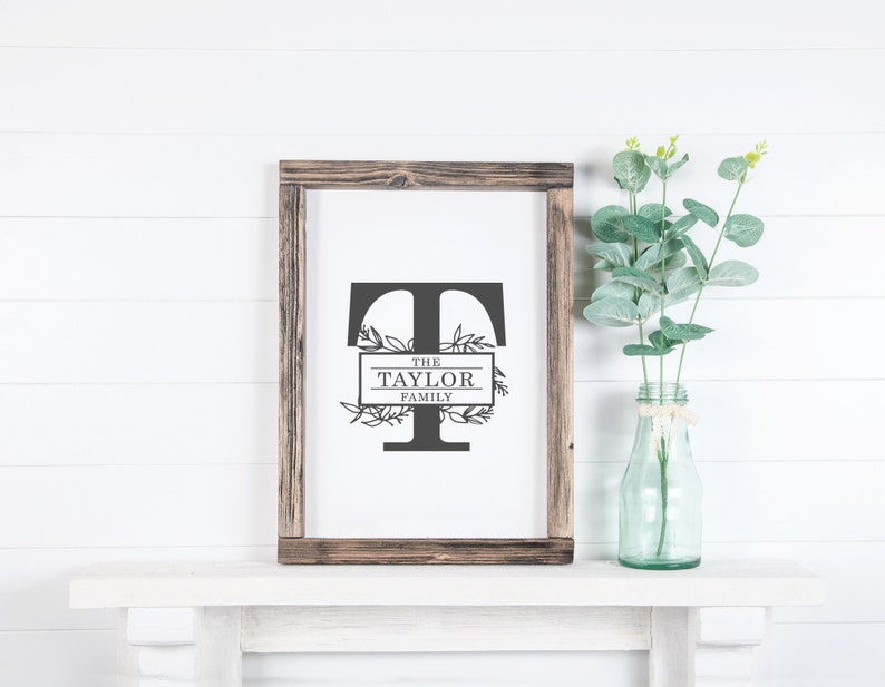 May include: A framed print with a black and white graphic of the letter T with floral accents. The text "The Taylor Family" is inside a rectangle below the letter T.
