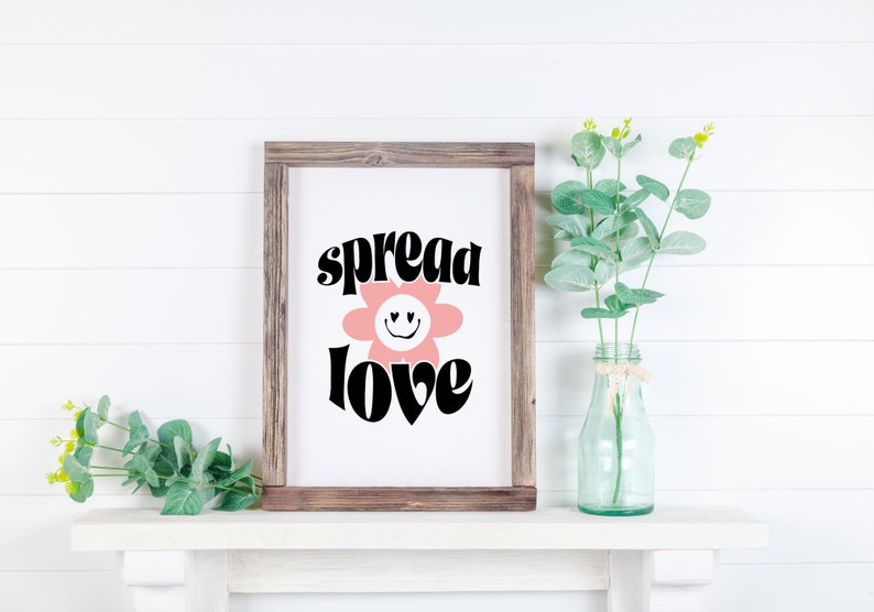 May include: A framed print with a pink flower with a smiley face and the text "spread love" in black letters.