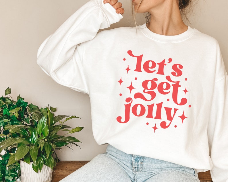 May include: White sweatshirt with a red graphic that says "Let's get jolly" with stars around the text.