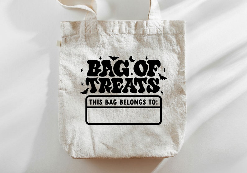 K&ouml;nnte beinhalten: Eine wei&szlig;e Stofftasche mit schwarzem Text, der in einer Retro-Schriftart "Bag of Treats" lautet. Die Tasche hat auch ein schwarzes Rechteck mit dem Text "This bag belongs to:" und einen leeren Platz zum Schreiben eines Namens.