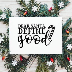May include: A white card with black text that reads "Dear Santa, Define Good" with a candy cane graphic next to the text. The card is surrounded by green pine branches with red berries and white snowflakes.
