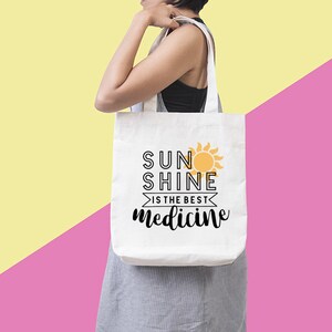 May include: White tote bag with black text that reads "Sunshine is the best medicine" and a yellow sun graphic.