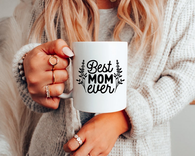 May include: White ceramic mug with black text that reads "Best Mom Ever" and a floral design.