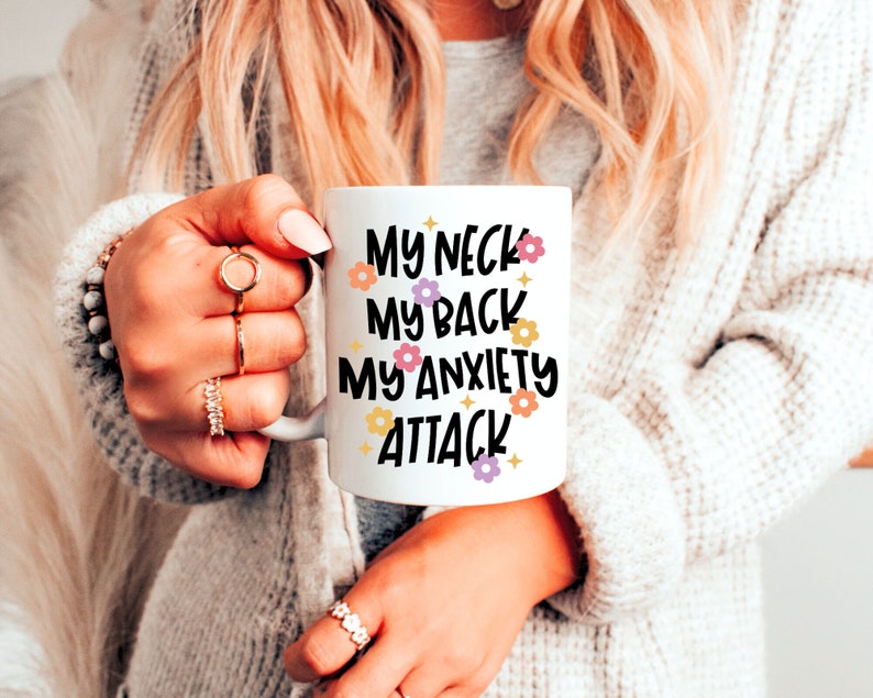 Pode incluir: Caneca de cer&acirc;mica branca com texto preto que diz "My neck, my back, my anxiety attack" com pequenas ilustra&ccedil;&otilde;es de flores.