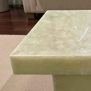 Puede incluir: Una mesa de centro rectangular verde claro con un patr&oacute;n similar al m&aacute;rmol. La mesa tiene una base s&oacute;lida y una superficie lisa y pulida. La mesa est&aacute; hecha de un material s&oacute;lido y es adecuada para una sala de estar.