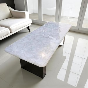 Könnte beinhalten: Rechteckiger Couchtisch mit weißer Marmorplatte und dunkelbraunem Sockel. Der Tisch befindet sich in einem modernen Wohnzimmer. Die Abmessungen betragen ca. 150 cm Länge und 75 cm Breite.