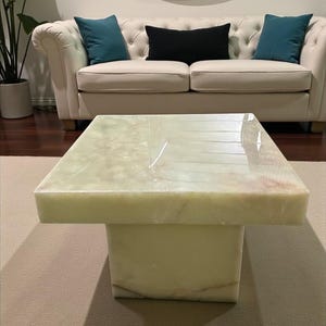 Handmade onyx coffee table featuring a polished natural stone slab on a low plinth stand, styled for modern living room interiors