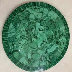 Puede incluir: Un plato decorativo redondo con un diseño de mosaico. El plato está hecho de piedra de malaquita verde, con un acabado pulido. El patrón de mosaico está formado por piezas irregulares de malaquita, creando un diseño único y llamativo, de unos 30 cm de diámetro.