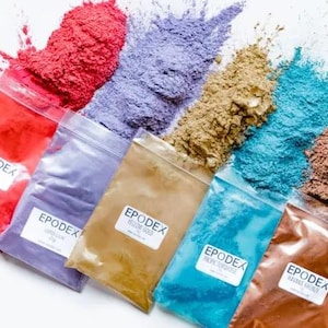 May include: A selection of coloured epoxy resin powders in clear plastic bags. The powders are red, purple, gold, turquoise, and brown. Each bag has a label with the word "EPODEX".