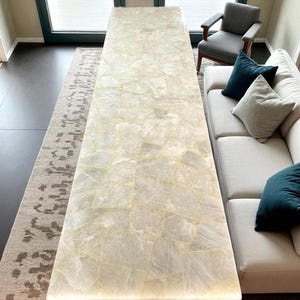 Può includere: Un lungo tavolo rettangolare con una superficie chiara a mosaico. Il tavolo è sostenuto da gambe marrone scuro e si trova in una stanza ben illuminata. Il tavolo misura circa 254 cm di lunghezza.