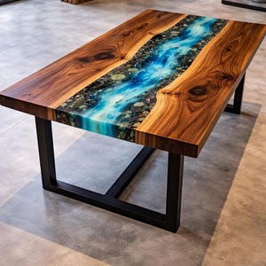 Op de afbeelding: Rechthoekige salontafel van hout met een rivierontwerp. Het midden is gevuld met blauwe en witte hars en stenen. De tafel heeft een zwart metalen onderstel. Het houten frame is donkerbruin.
