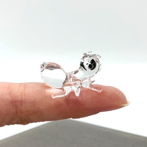 May include: A clear glass ant figurine with black eyes. The ant is posed as if it is walking.