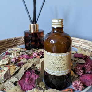 Peut inclure: Une bouteille en verre brun avec un bouchon doré, remplie d'un liquide clair. La bouteille porte une étiquette sur laquelle est inscrit "HAND POURED IN SCOTLAND MELT POOL APOTHECARY BERGAMOT, CLOVE & EUCALYPTUS SCENTED WITH ESSENTIAL OILS".