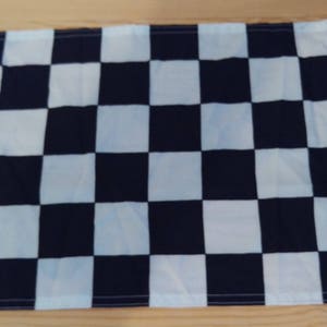 Könnte beinhalten: Eine schwarz-weiße karierte Flagge. Die Flagge ist aus Stoff und hat einen weißen Rand.