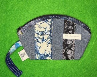Puede incluir: Pequeño neceser de tela vaquera y batik con cierre de cremallera. El neceser presenta paneles de tela vaquera azul y batik en blanco, azul y negro. El texto "Batik & Denim Bag LG1" es visible en una etiqueta blanca.