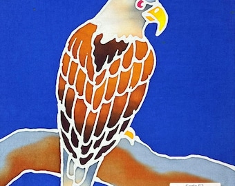 Puede incluir: Una pieza de arte textil que presenta un águila estilizada con cabeza blanca, pico amarillo y plumas en tonos marrones posada sobre una rama contra un fondo azul sólido. El águila tiene un ojo rojo y el texto Eagle E2 está en un recuadro.
