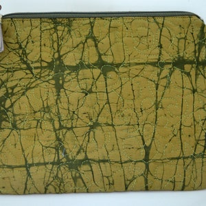 May include: A green quilted zippered pouch with a brown and white tassel. The pouch has a batik pattern and the text "TURTLE HANDS crafted in Malaysia" is printed on a white tag attached to the pouch.