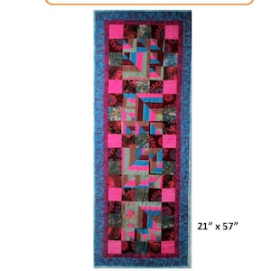 May include: A colourful quilt runner with a geometric pattern in shades of pink, blue, and brown. The runner is 21 inches by 57 inches and is titled "Mitered Mosaic Runner" with the product code HQ-248. The quilt is made by Woven Inspirations by Highview Quiltworks.