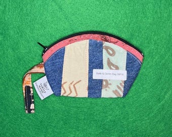 Puede incluir: Pequeño bolso Batik y denim colorido con cremallera negra y correa de muñeca. El bolso presenta un diseño de patchwork con mezclilla azul, crema y tela azul claro. El texto "Batik & Denim Bag SM19" es visible.